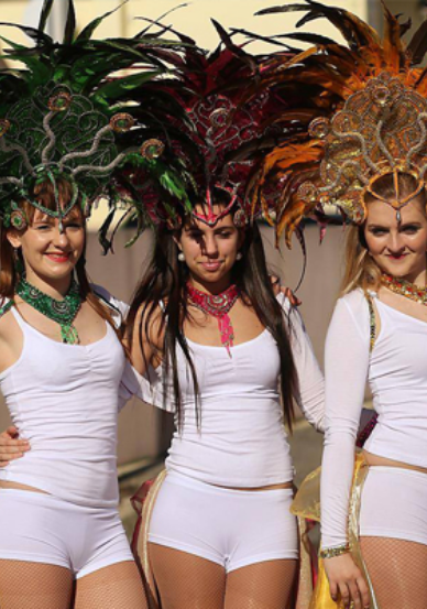 Trois danseuses habillées de blanc avec des coiffes en plume